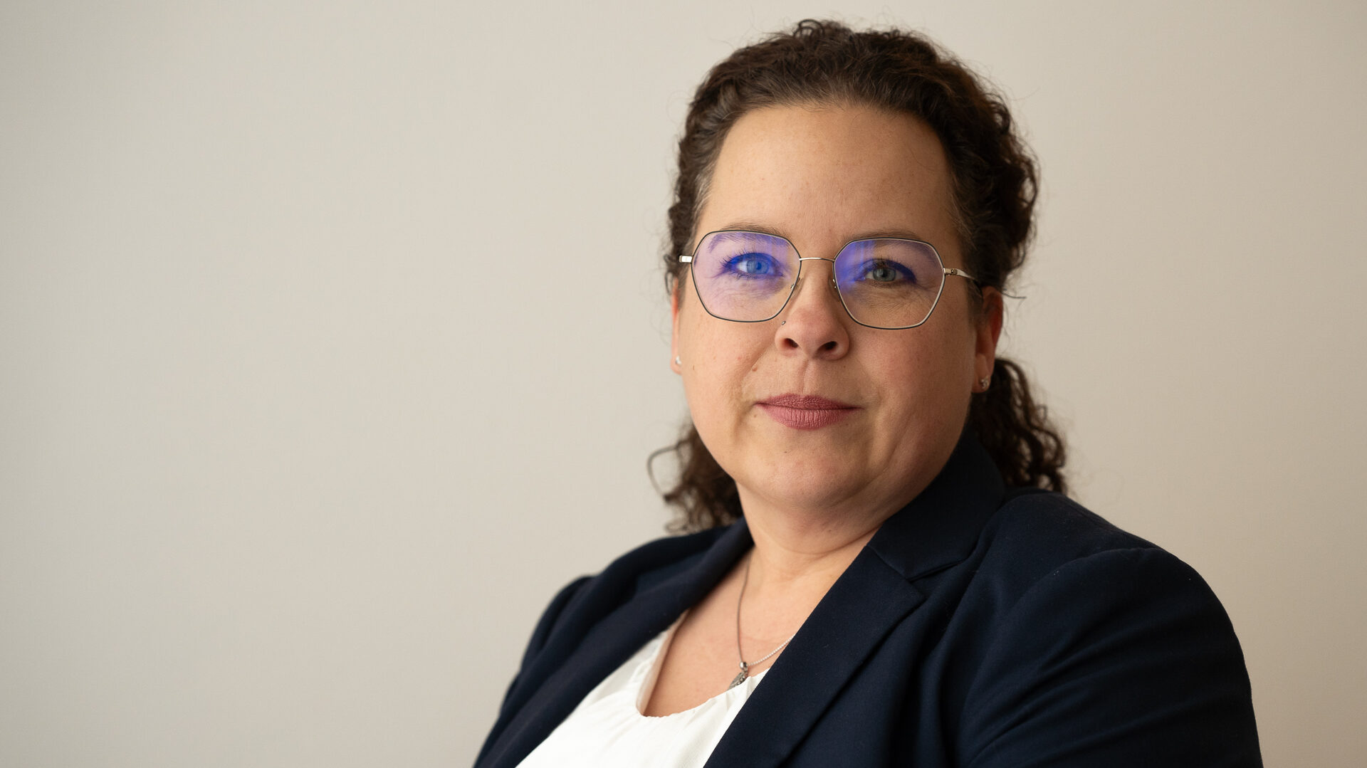 Eine Frau mit Brille und Locken schaut in die Kamera